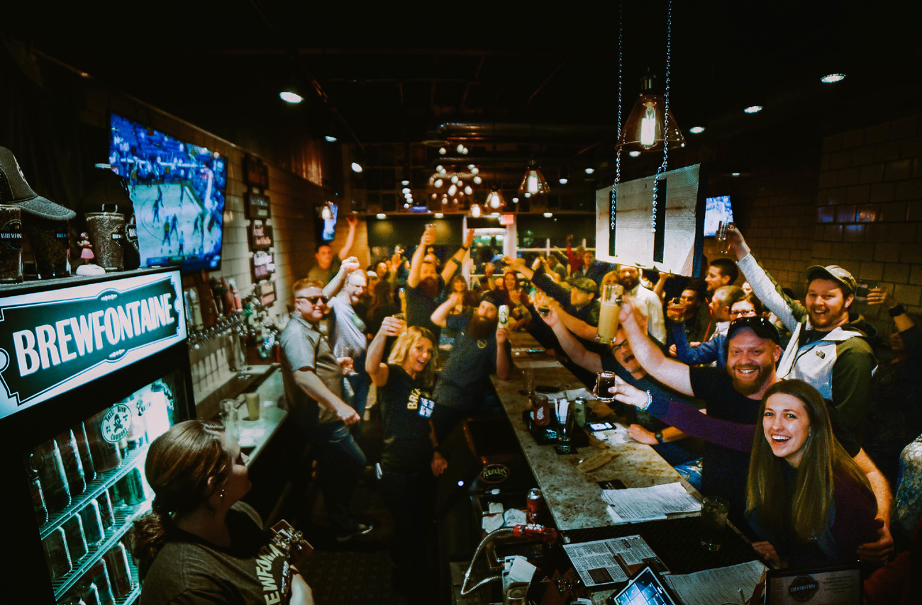 Brewfontaine staff and customers raise their glasses in a toast.